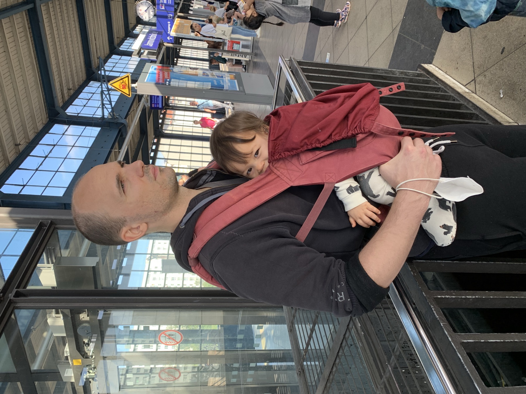 Mia figlia nel marsupio bordeaux guarda di lato mentre io tengo entrambe le mani libere.