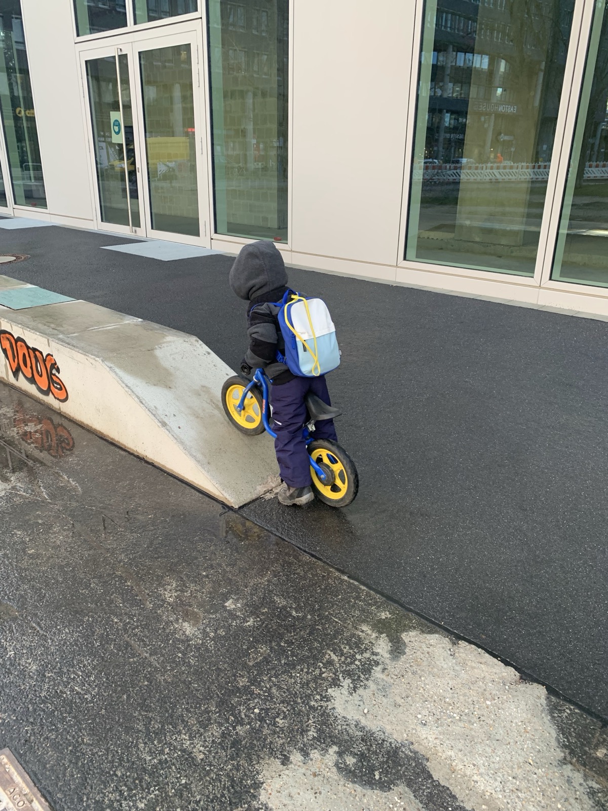 Mein Sohn schiebt das Laufrad eine kleine Betonrampe hinauf.