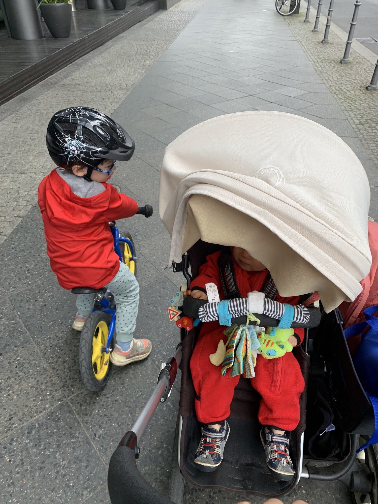 My son riding the balance bike while my daughter sits in the stroller.