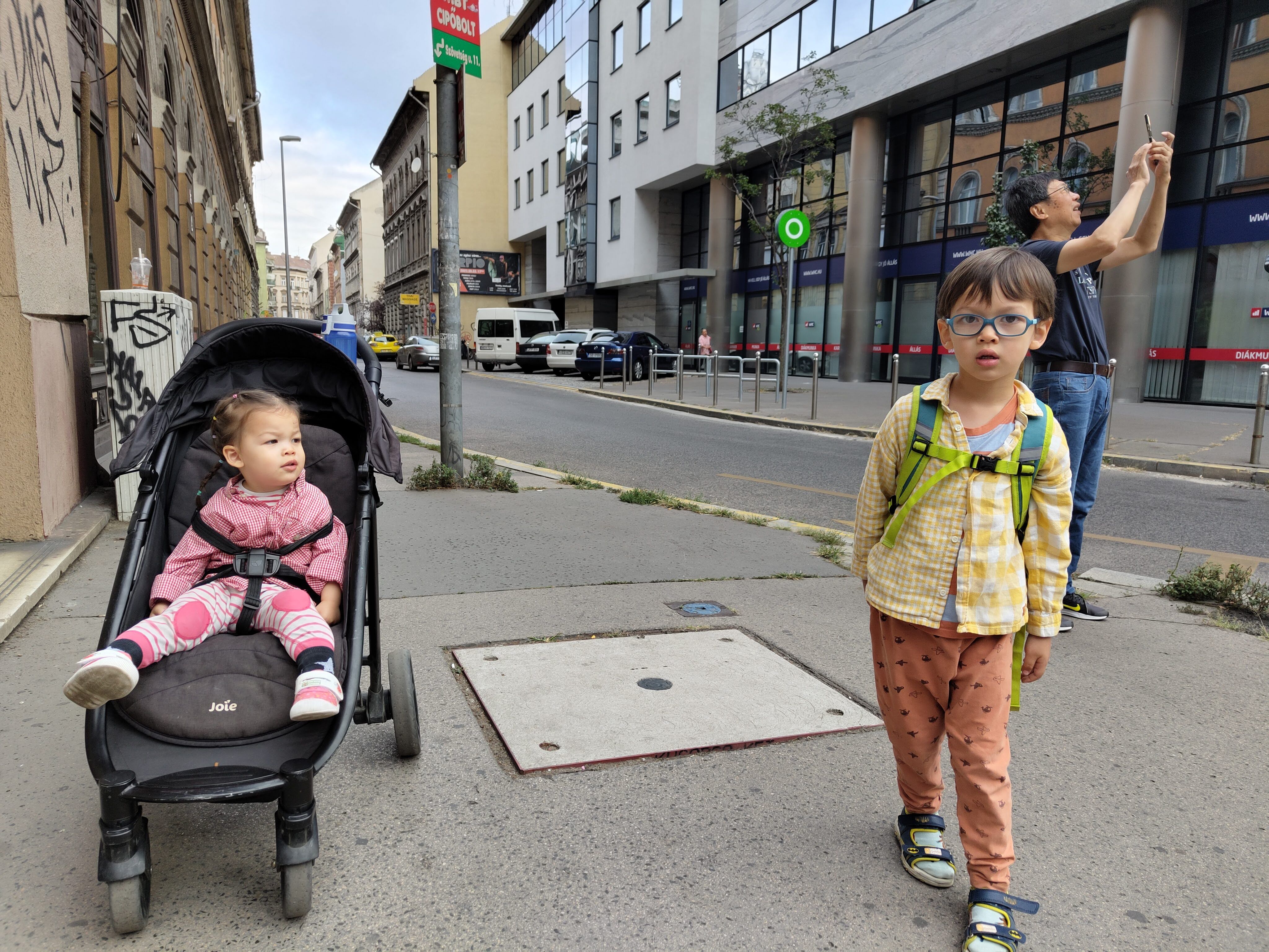 My daughter in her stroller and my son standing beside her on a Budapest city street during our family trip.