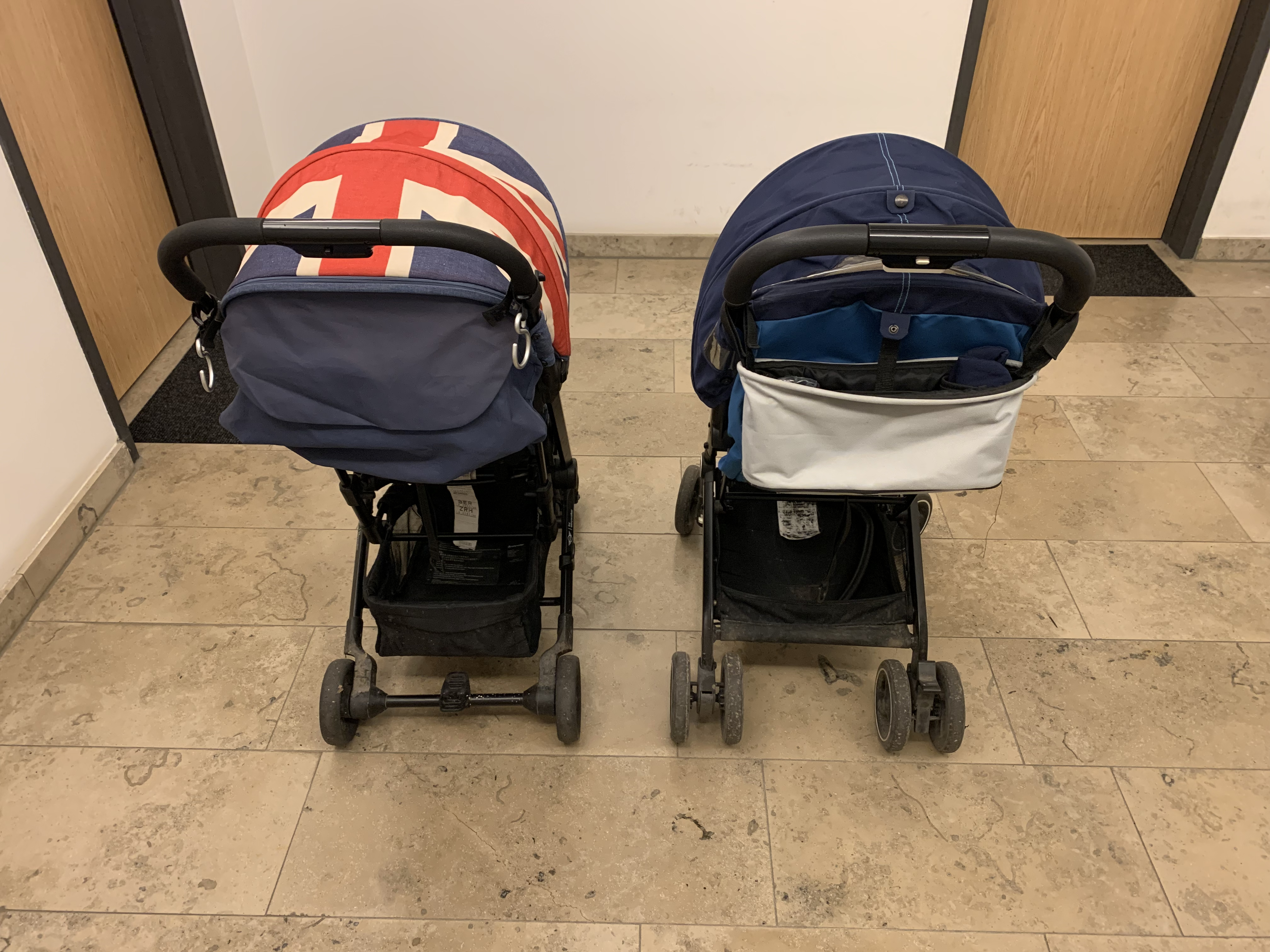 The two strollers from behind, showing the wider-looking wheel setup and basket area on the GB Qbit+ beside the slimmer Easywalker Buggy XS.