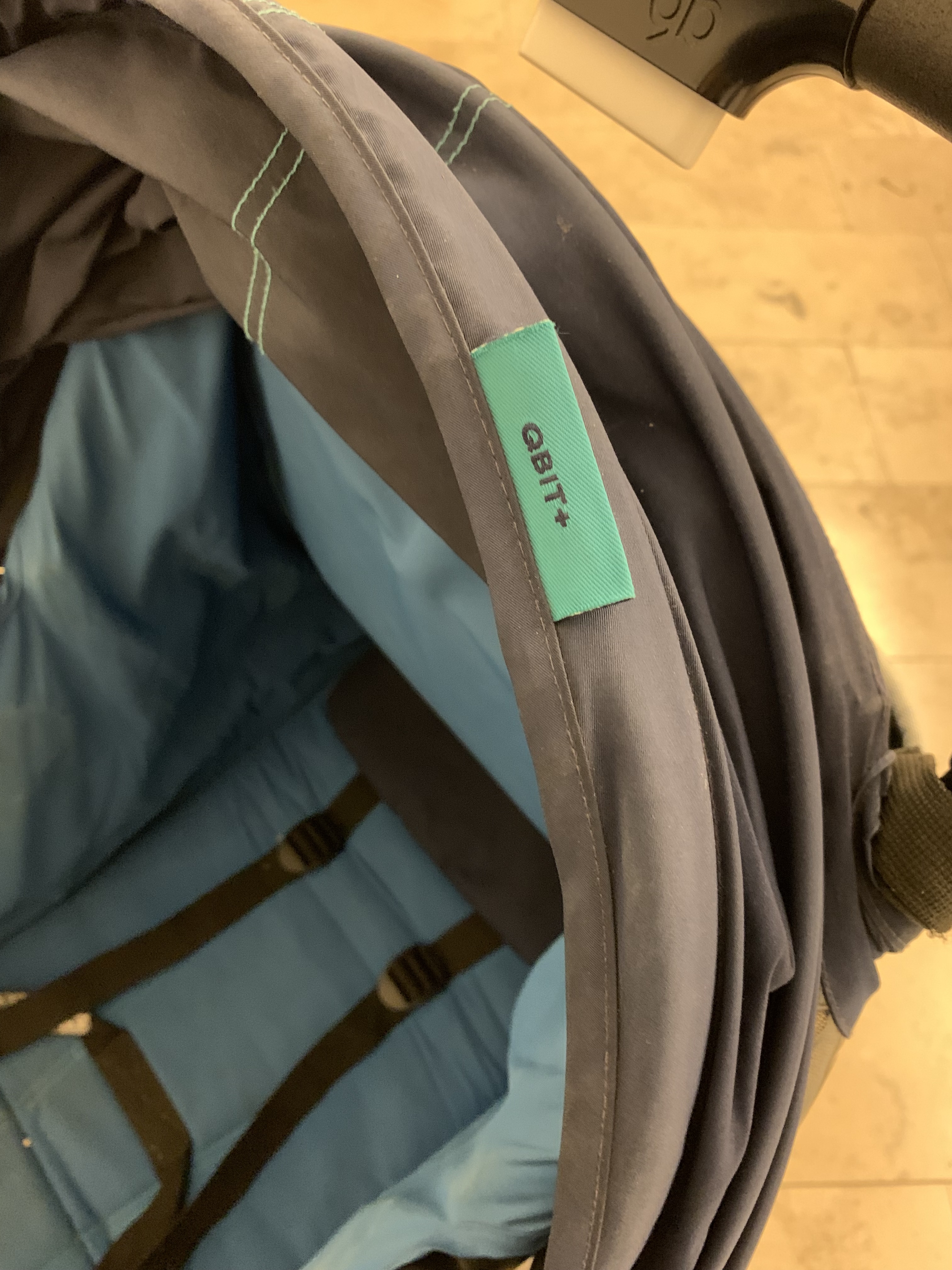 A close view of the GB Qbit+ label and canopy fabric, showing the real used condition rather than a showroom stroller.