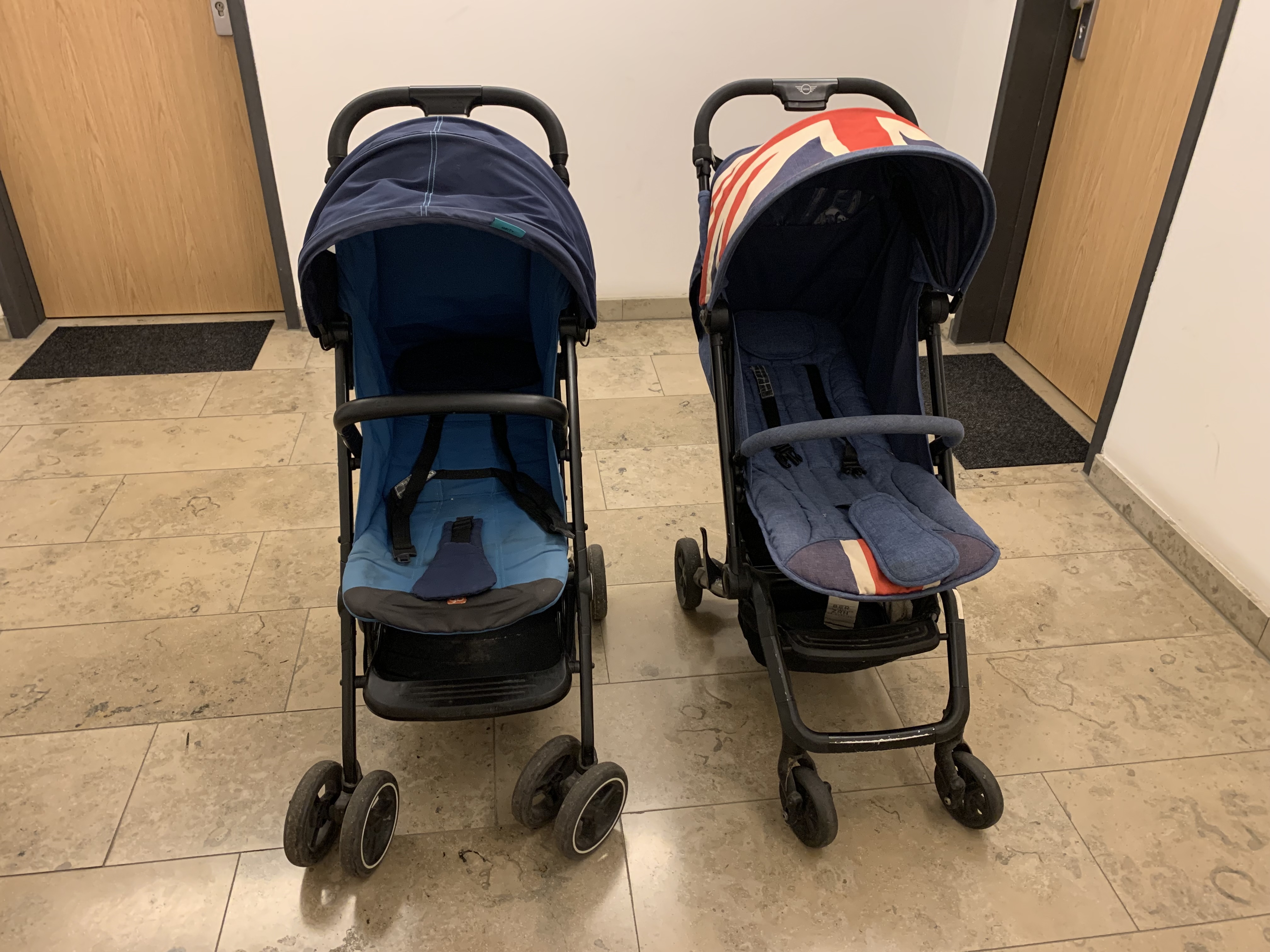 The two compact stroller seats from the front, showing the GB Qbit+’s simpler blue seat beside the Easywalker’s padded blue seat liner.