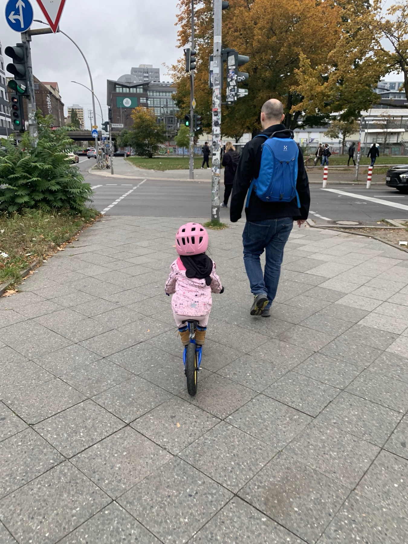 My daughter in a pink helmet waiting near a city crossing.
