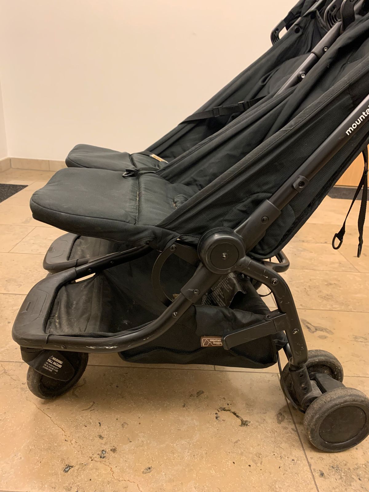 Mountain Buggy Nano Duo de profil, avec petites roues, cadre léger et sièges en tissu.