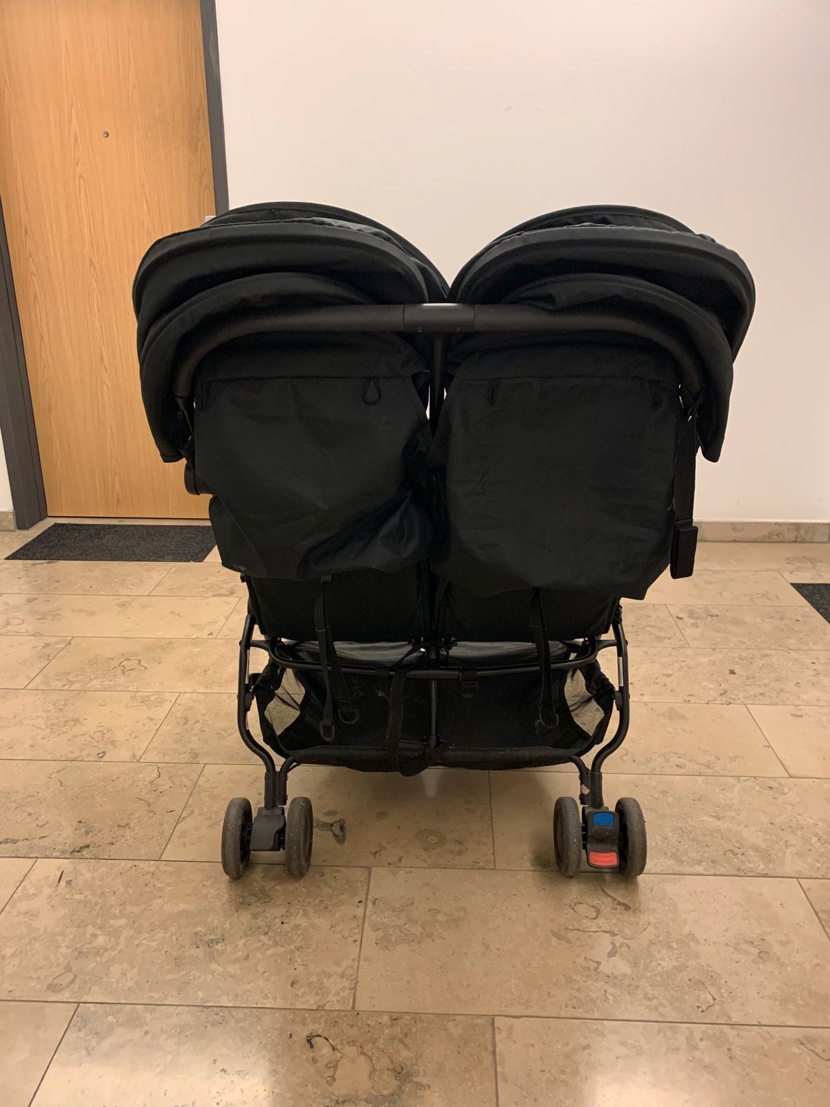 Mountain Buggy Nano Duo vue arrière, avec format côte à côte étroit, guidon commun et petites roues.