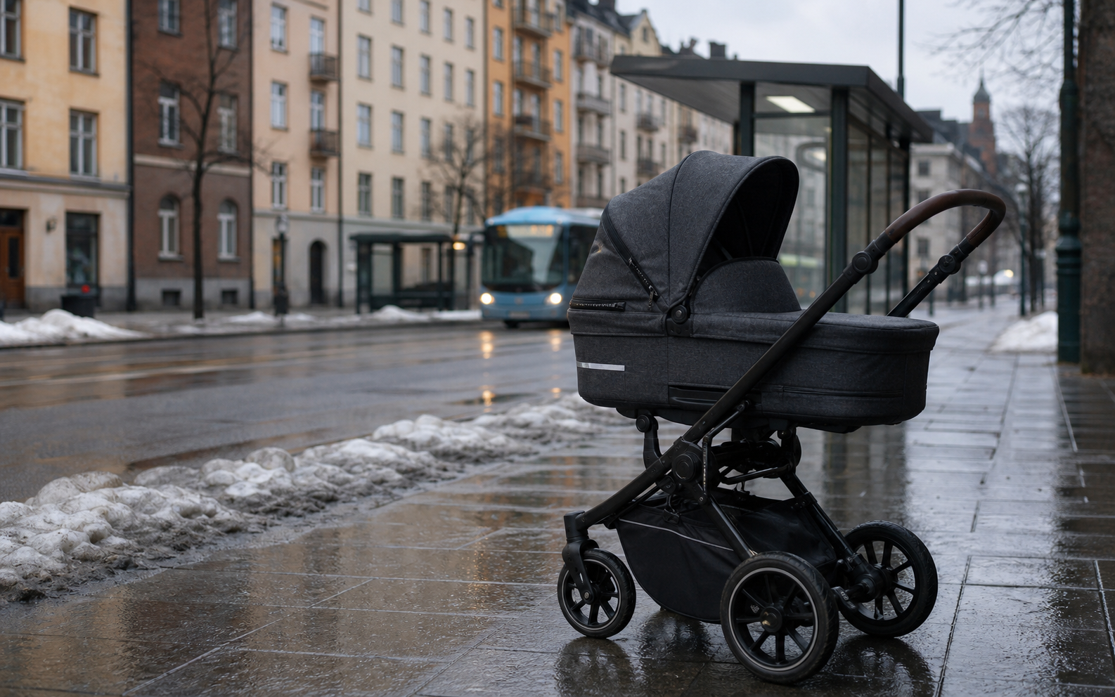 A bassinet stroller on a wet Swedish city sidewalk near a transit stop in late winter.