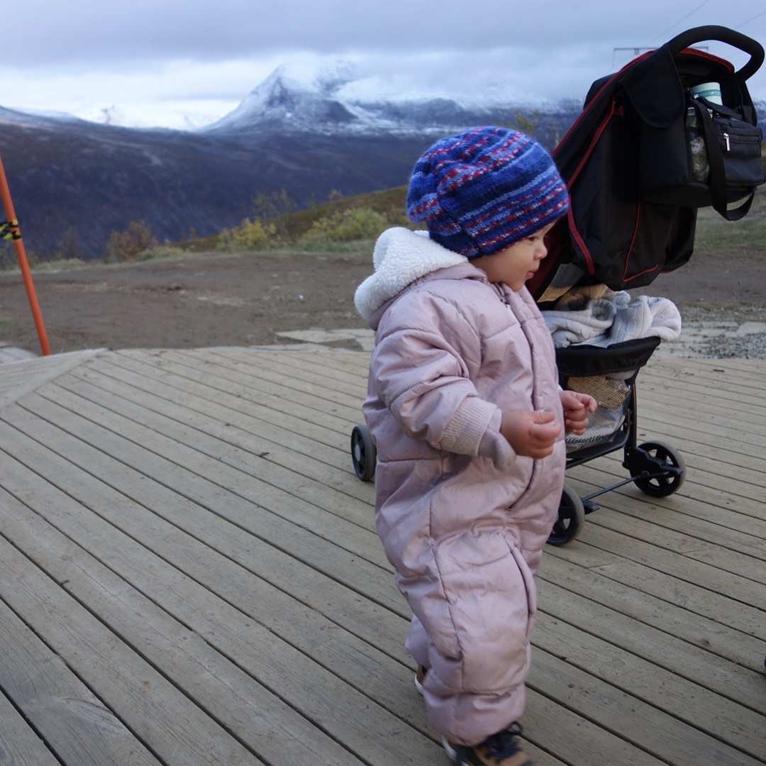 Mein Sohn auf der Aussichtsterrasse am Storsteinen, mit unserem kompakten Reisebuggy hinter ihm und Bergen in der Ferne.