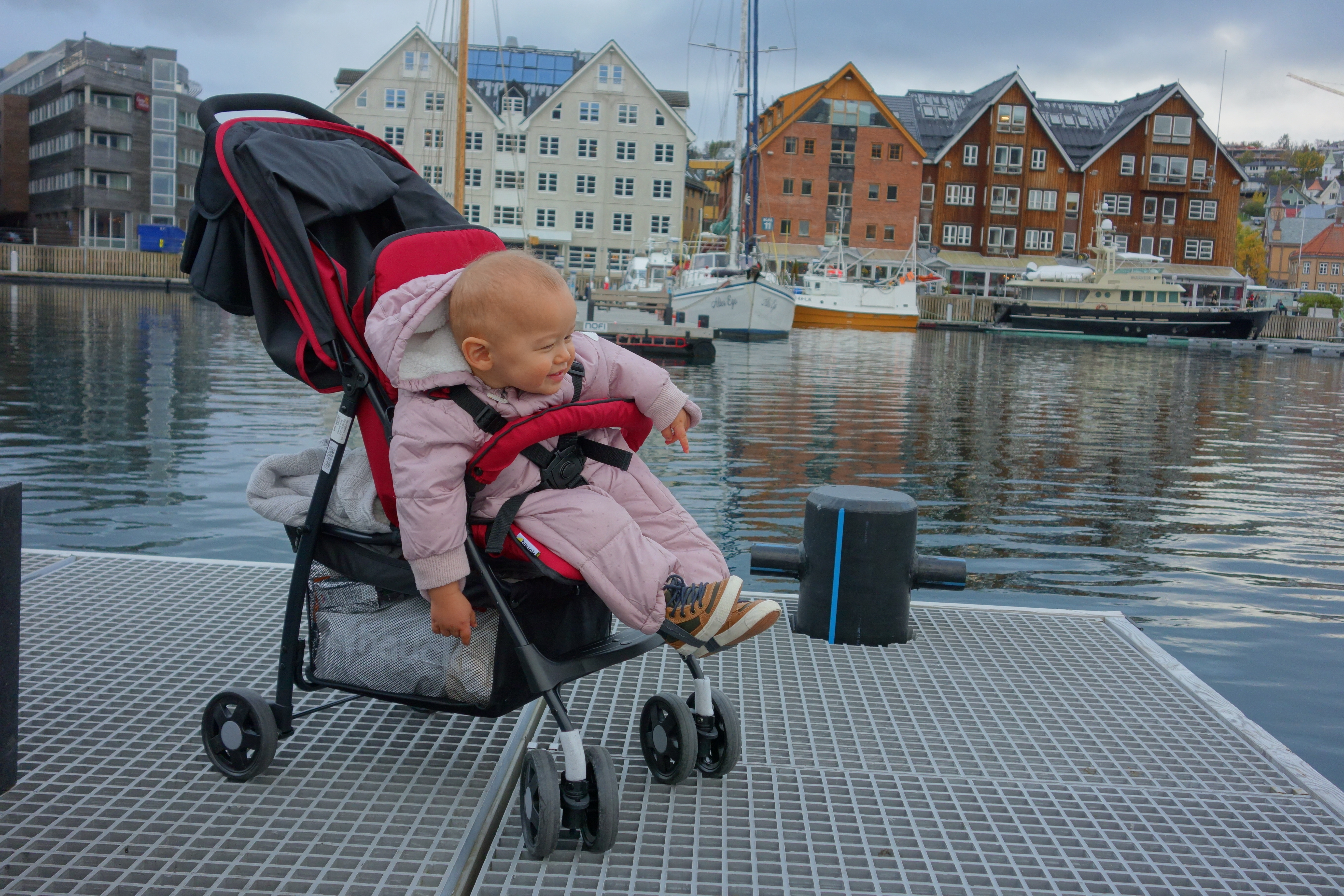 Unser Reisebuggy neben bunten Hafengebäuden in Tromso, ein guter erster Test für Wege mit Kleinkind.