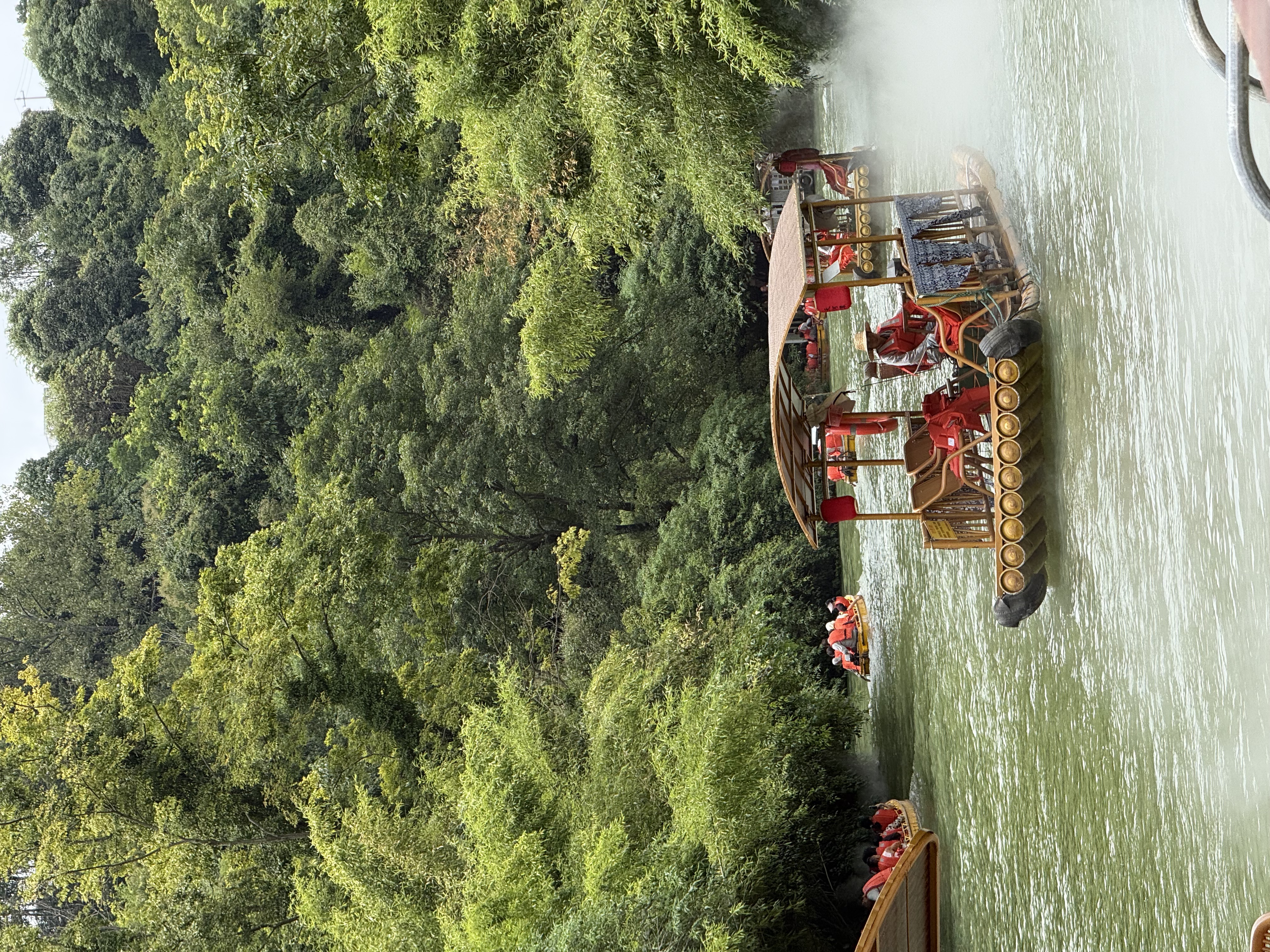 A covered raft on green water between wooded banks at Tianhetan.