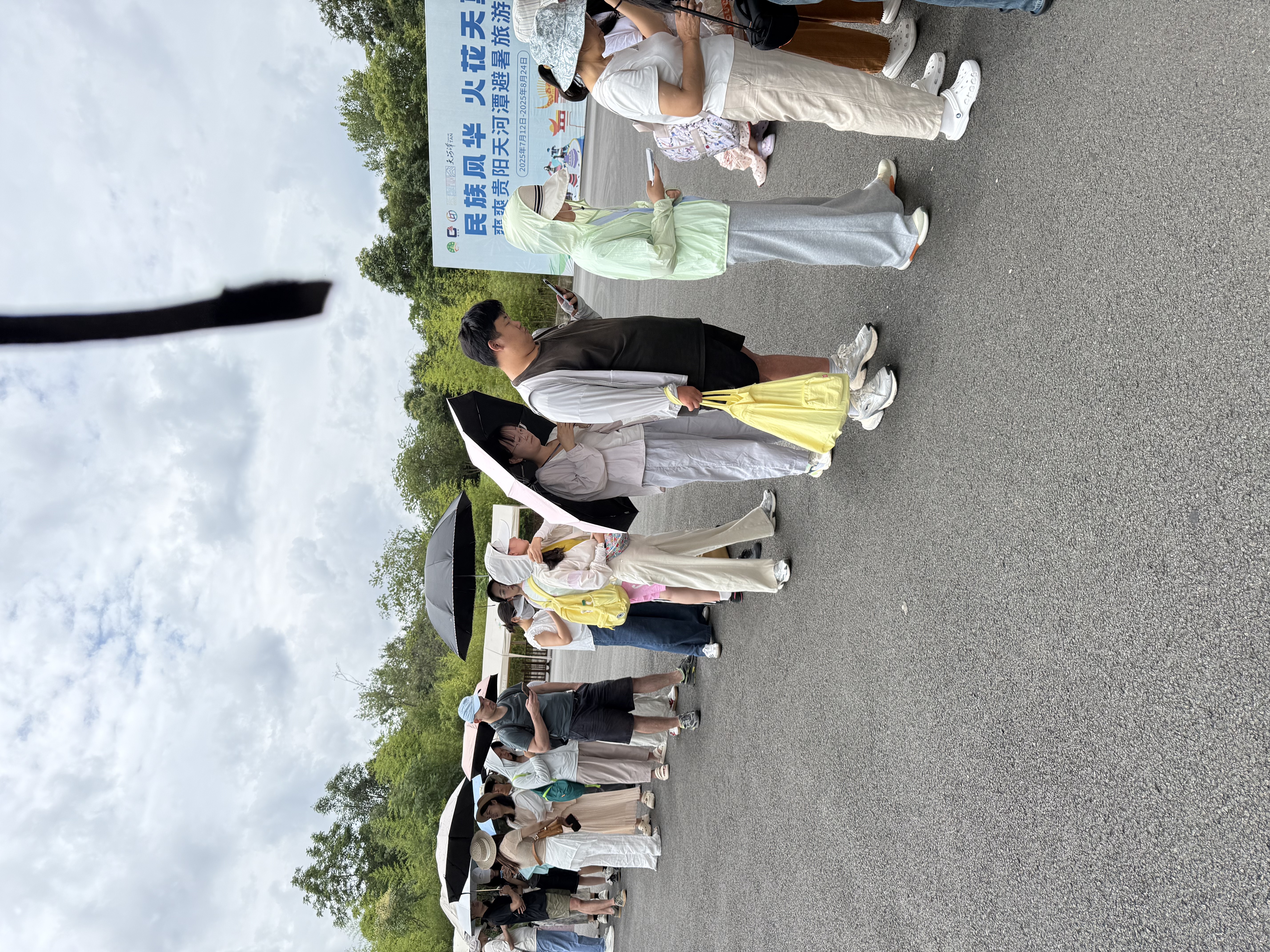 I queue with other visitors to buy tickets at Tianhetan, with umbrellas all around us.